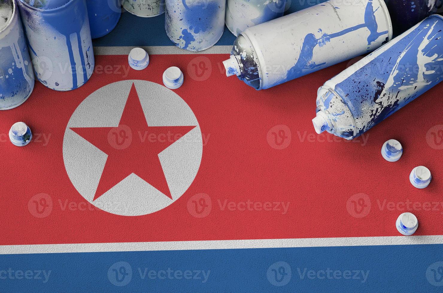 North Korea flag and few used aerosol spray cans for graffiti painting. Street art culture concept photo