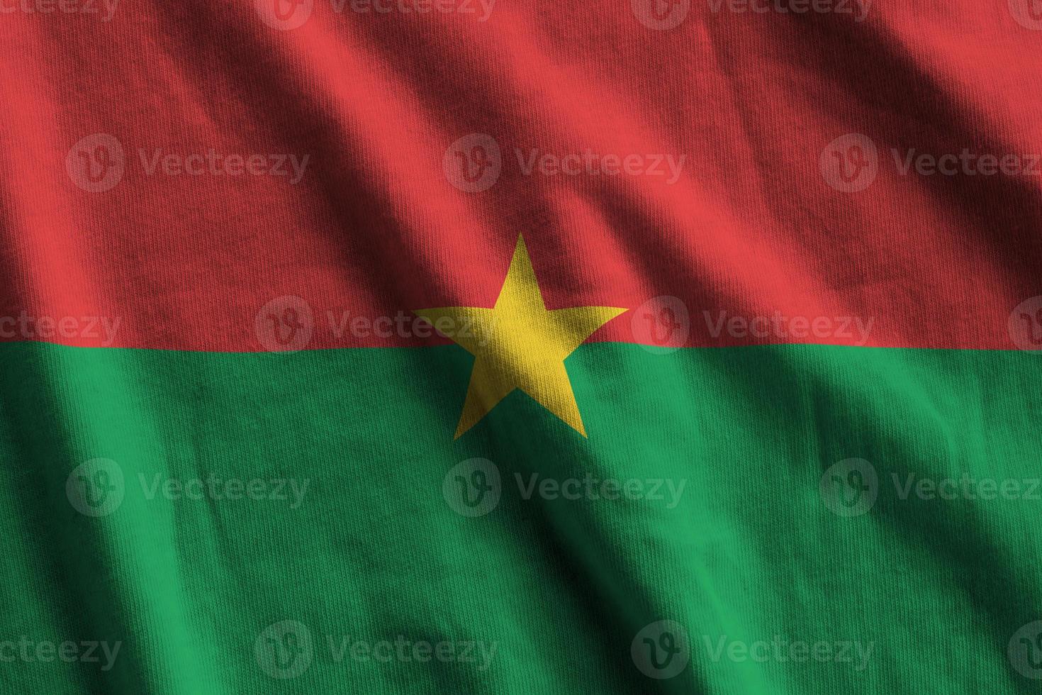 Burkina Faso flag with big folds waving close up under the studio light indoors. The official symbols and colors in banner photo