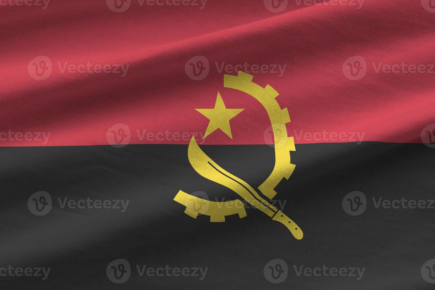 bandera de angola con grandes pliegues ondeando de cerca bajo la luz del estudio en el interior. los símbolos y colores oficiales en banner foto