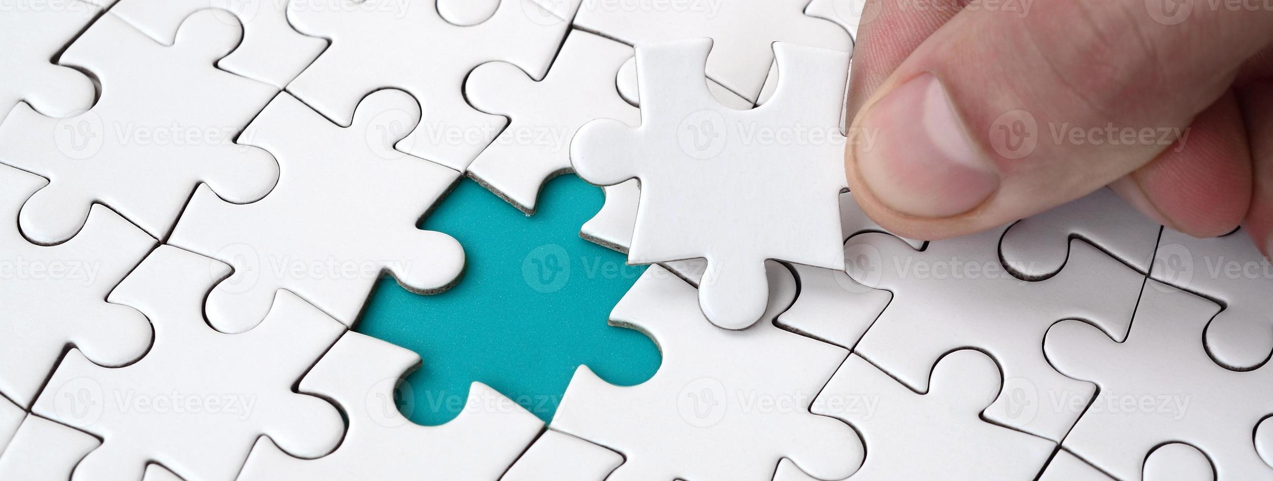 The human hand fills the last missing elements of the surface from the jigsaw puzzle. The concept of the completion of the initiated cases photo