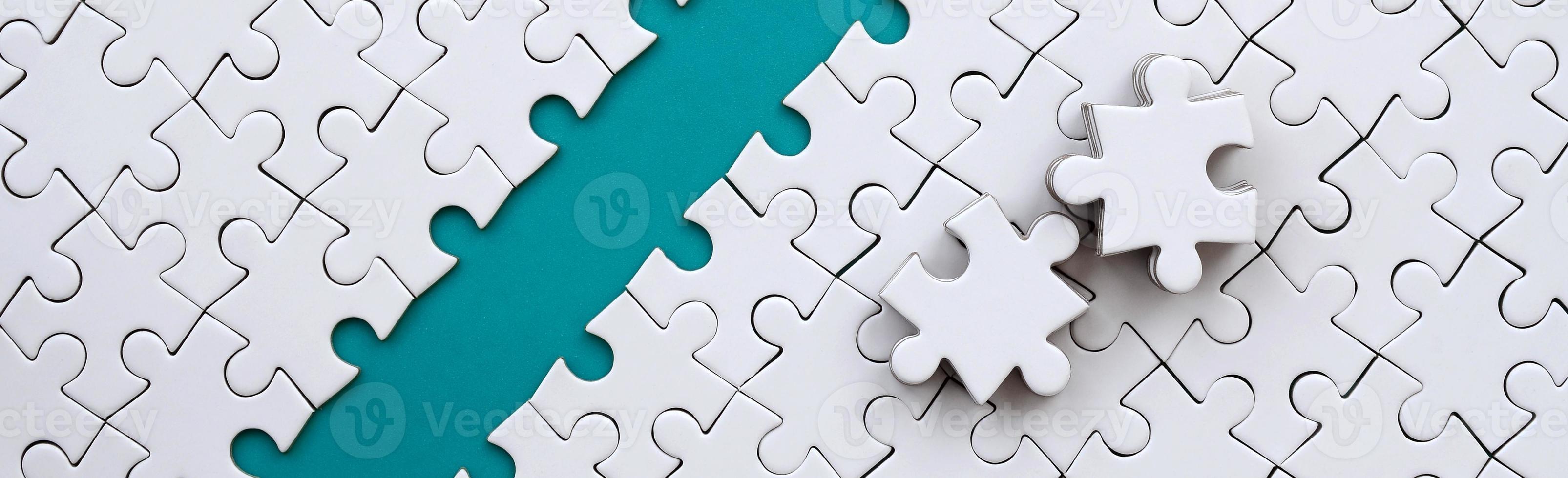 The blue path is laid on the platform of a white folded jigsaw puzzle. The missing elements of the puzzle are stacked nearby. Texture image with space for text photo