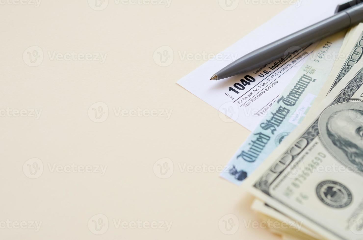1040 Individual Income tax return form with Refund Check and hundred dollar bills on beige background photo