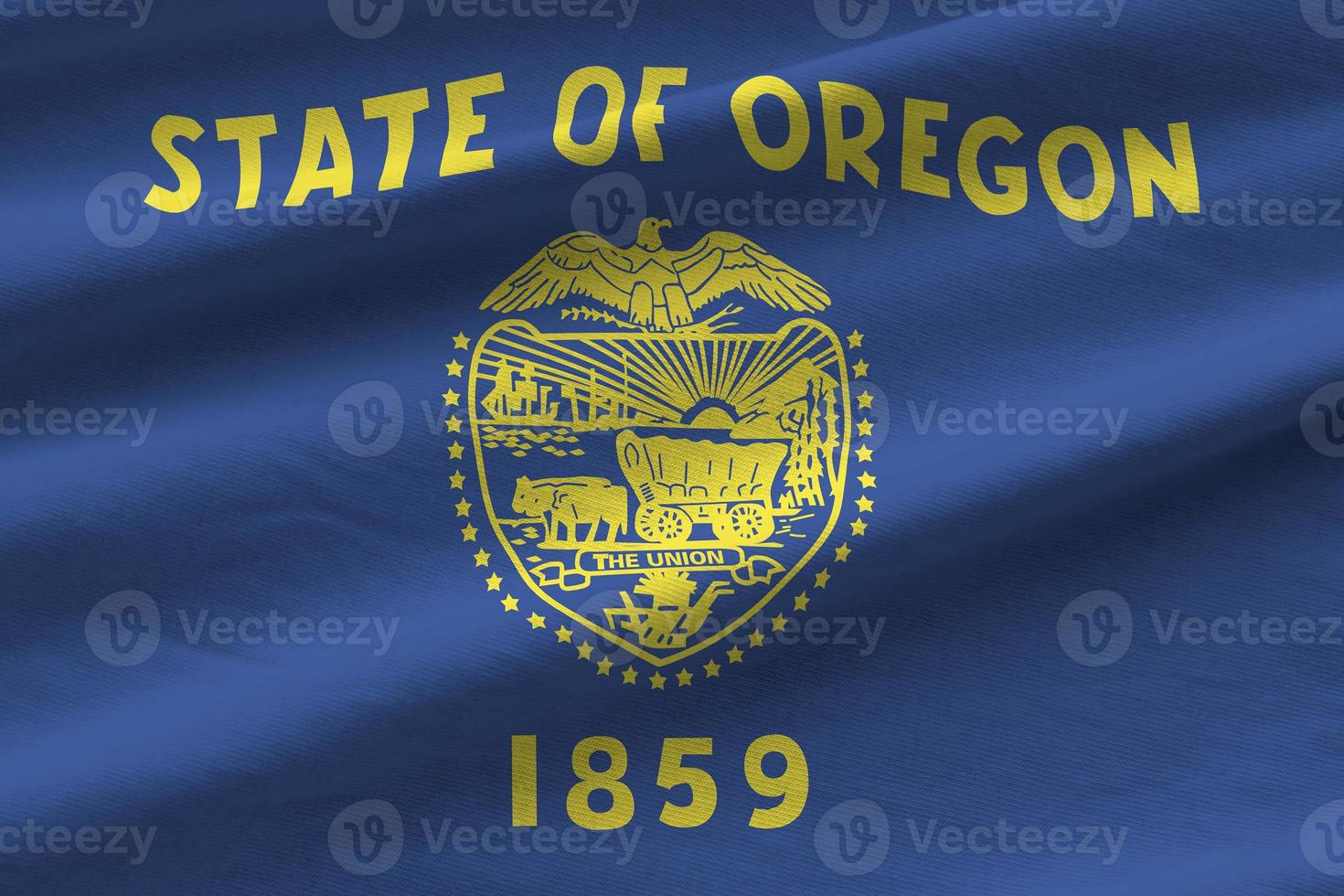 Oregon US state flag with big folds waving close up under the studio light indoors. The official symbols and colors in banner photo
