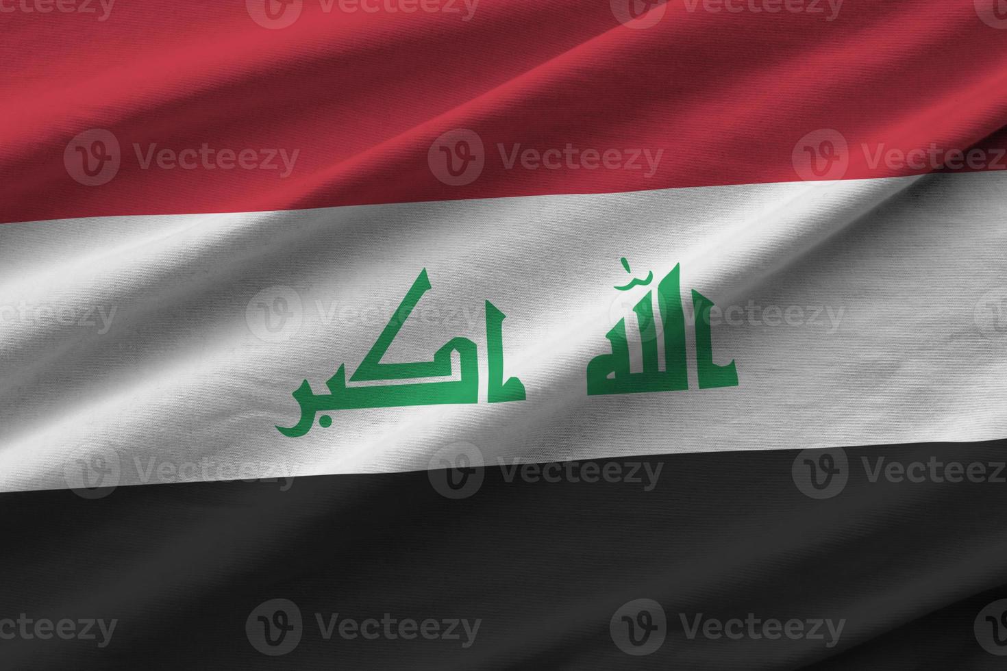 Iraq flag with big folds waving close up under the studio light indoors. The official symbols and colors in banner photo