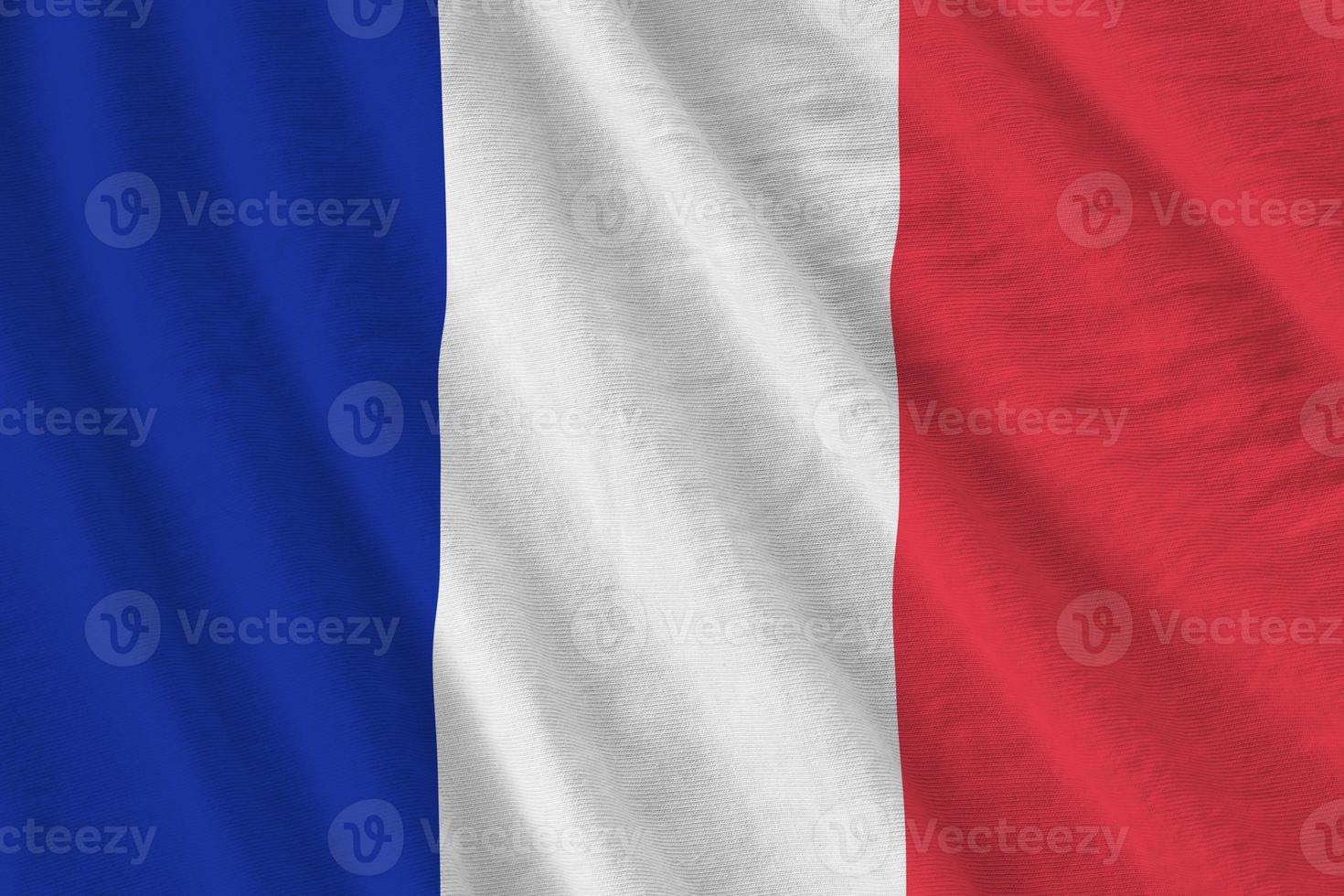 France flag with big folds waving close up under the studio light indoors. The official symbols and colors in banner photo