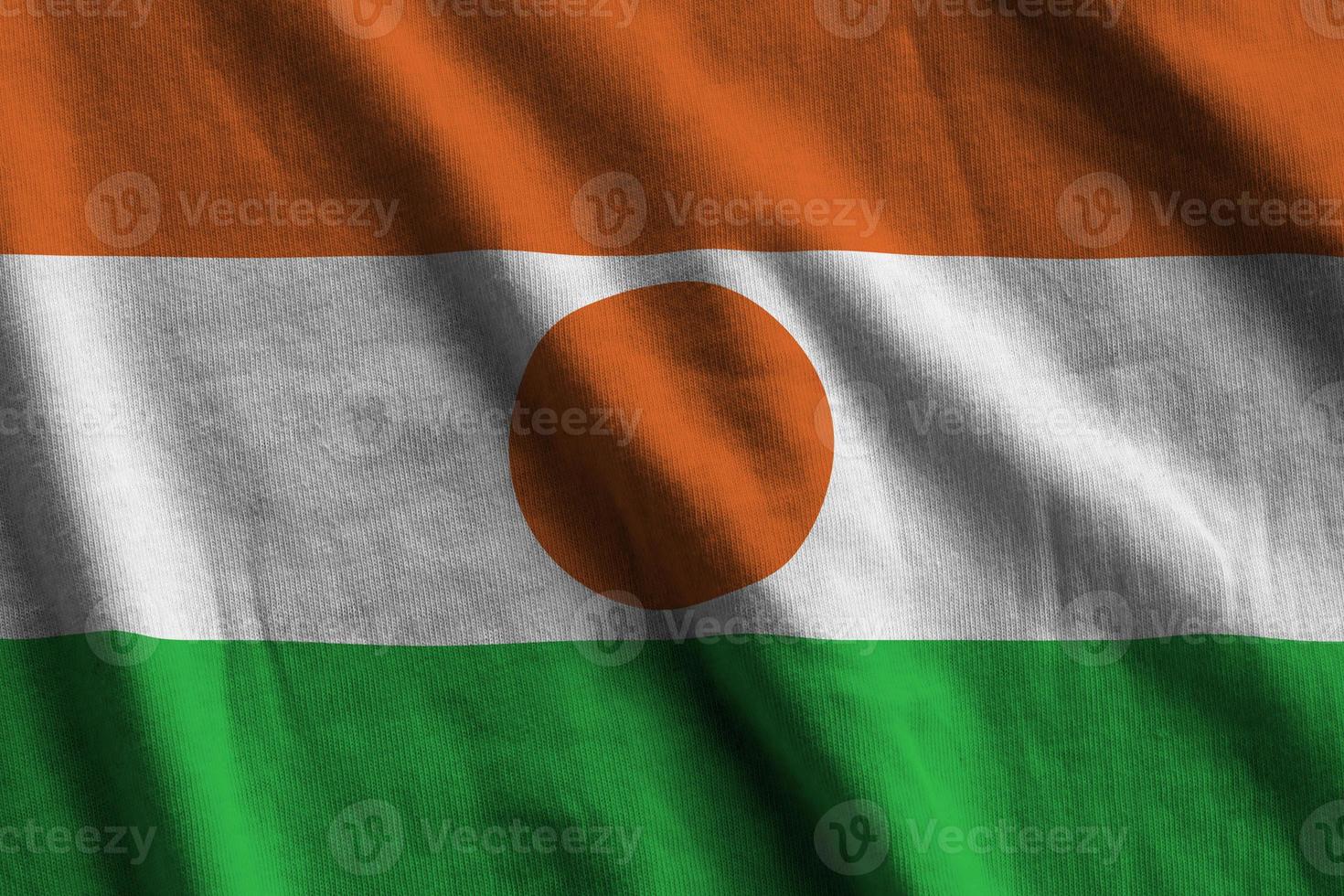 Niger flag with big folds waving close up under the studio light indoors. The official symbols and colors in banner photo