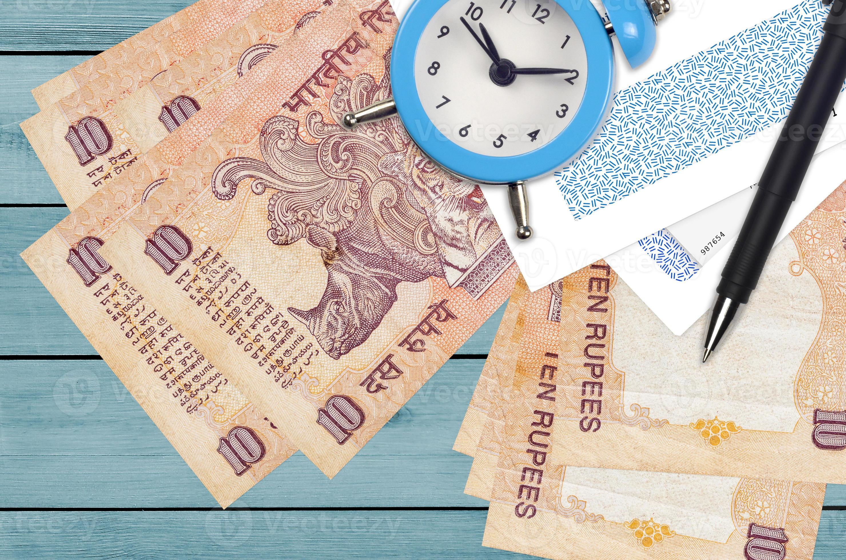 10 Indian rupees bills and alarm clock with pen and envelopes. Tax