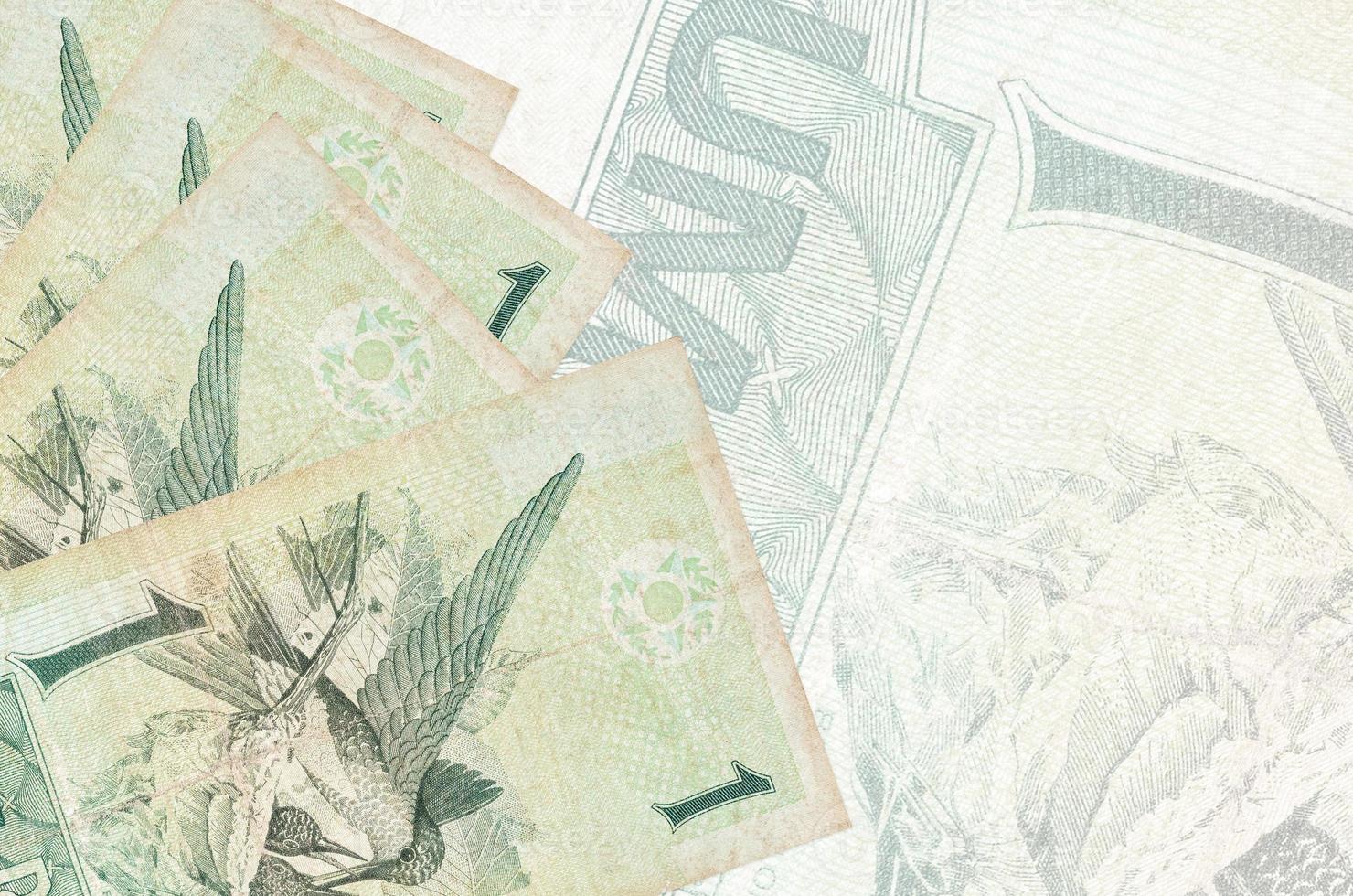 1 Brazilian real bills lies in stack on background of big semi-transparent banknote. Abstract business background photo