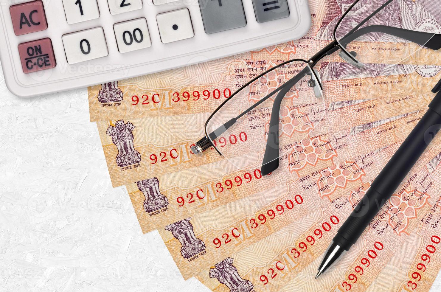 10 Indian rupees bills fan and calculator with glasses and pen. Business loan or tax payment season concept photo