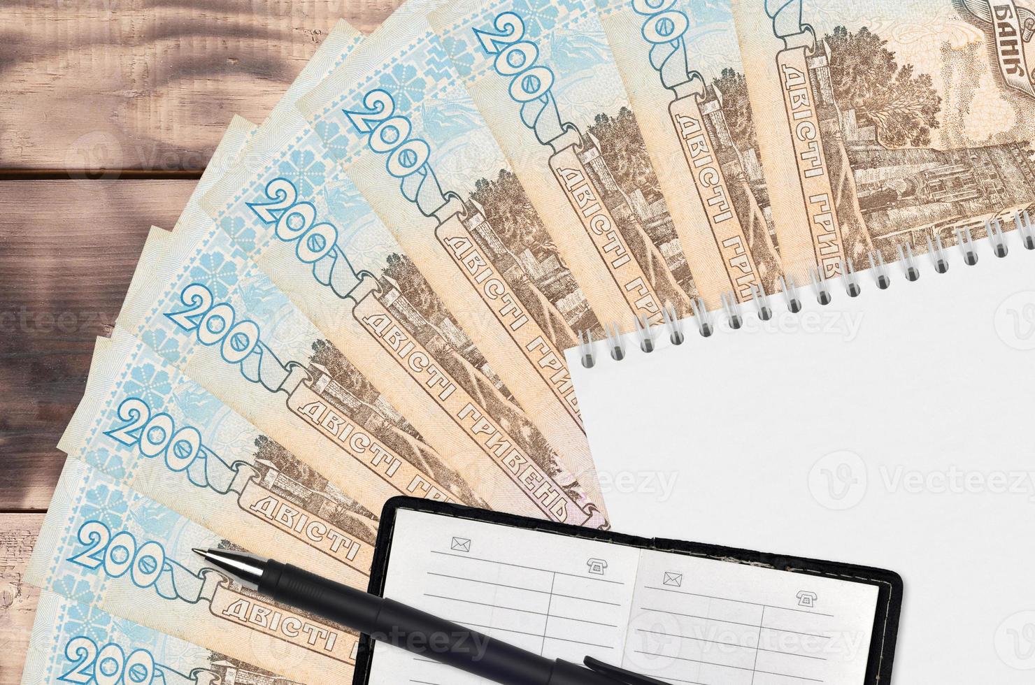 200 Ukrainian hryvnias bills fan and notepad with contact book and black pen. Concept of financial planning and business strategy photo