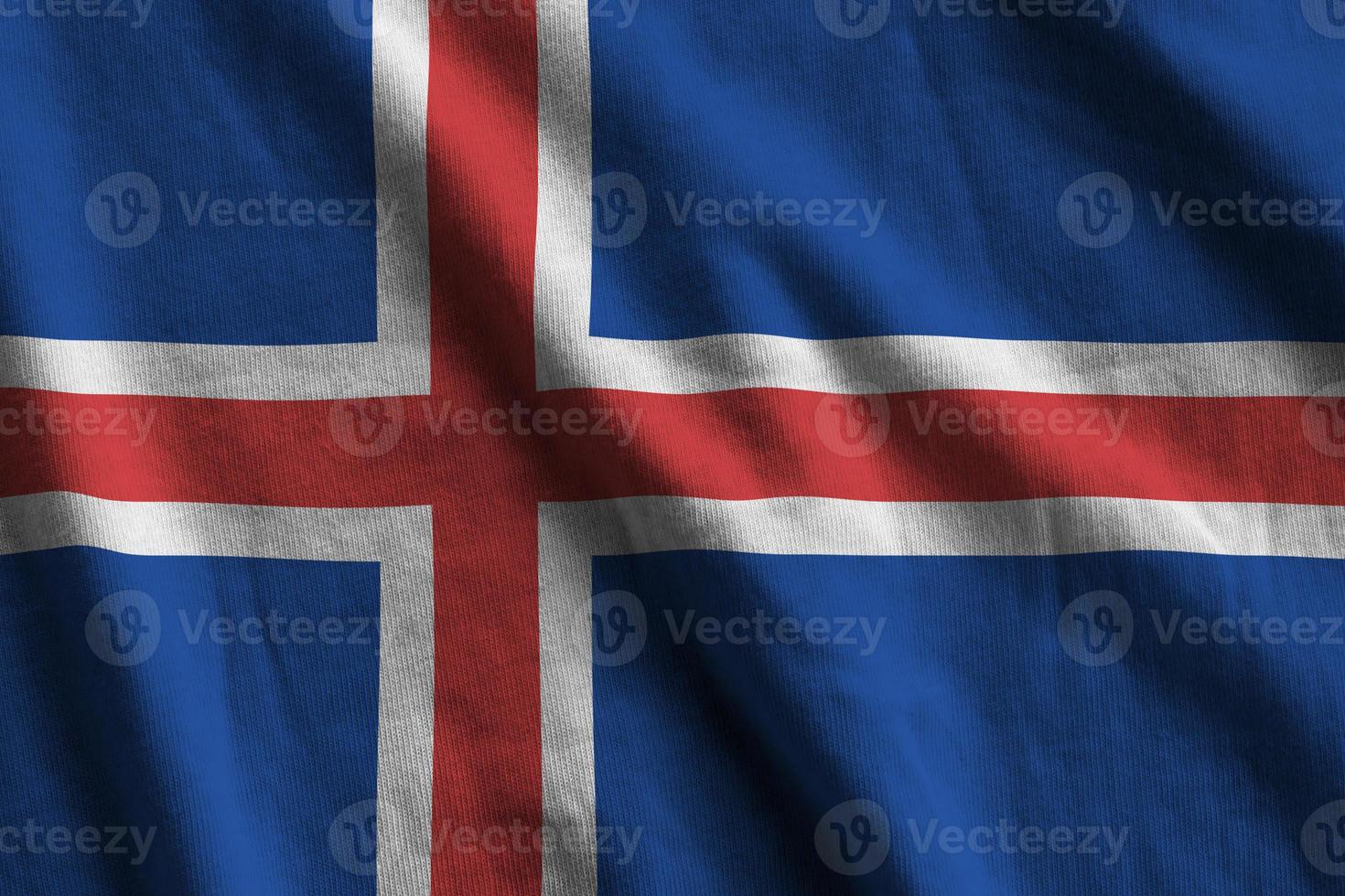 Iceland flag with big folds waving close up under the studio light indoors. The official symbols and colors in banner photo