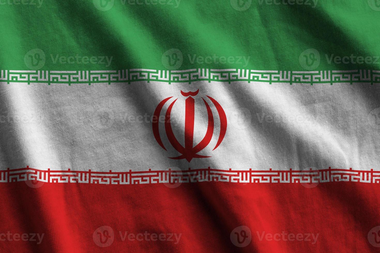 Iran flag with big folds waving close up under the studio light indoors. The official symbols and colors in banner photo