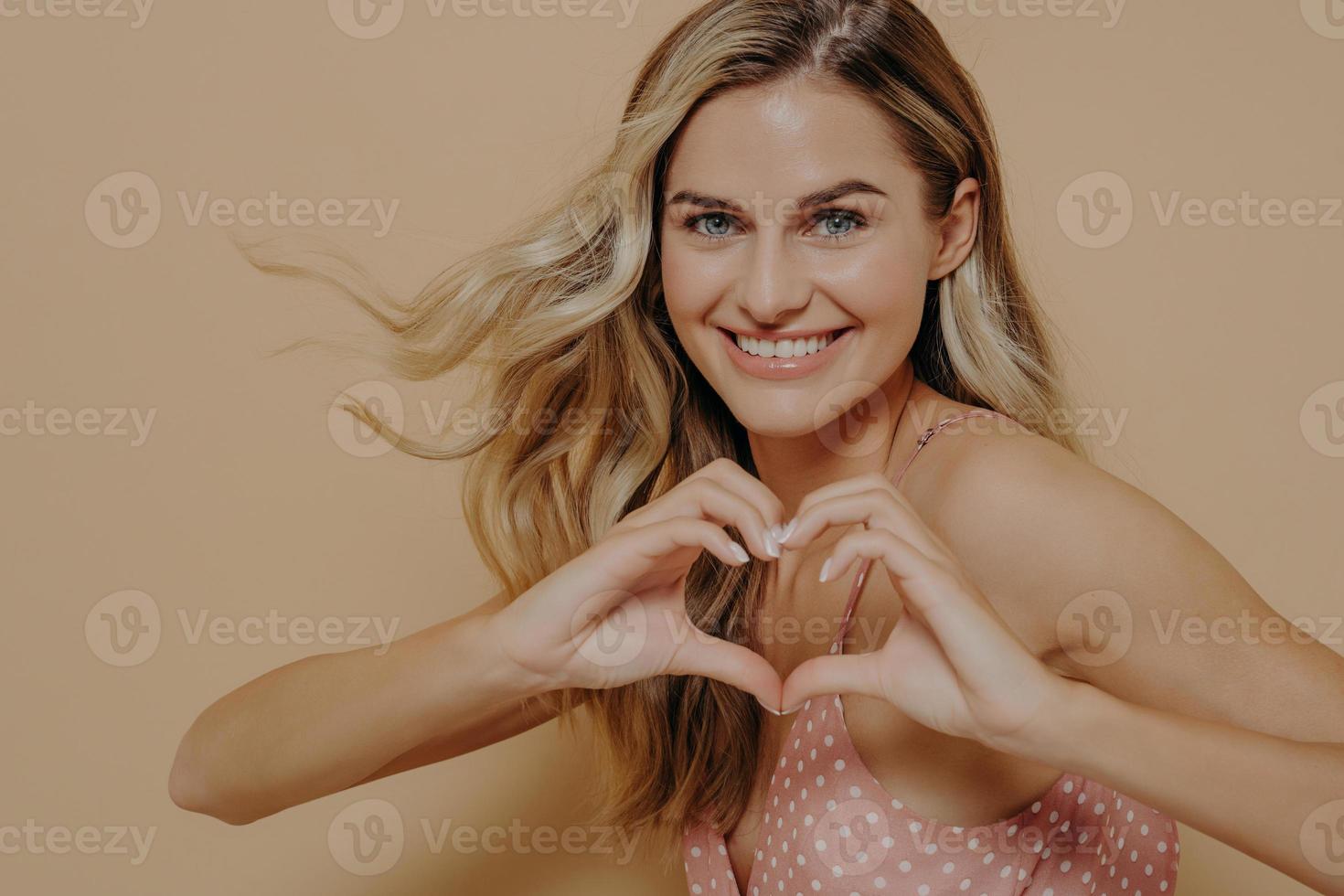 mujer rubia haciendo forma de corazón con sus manos foto