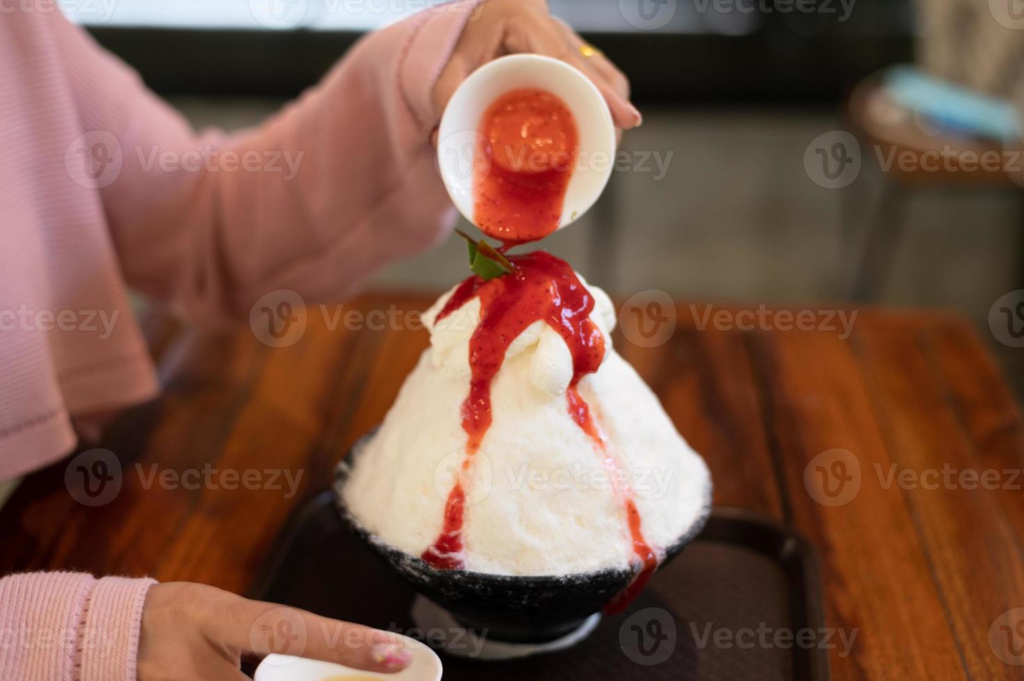 postre de hielo raspado coreano con coberturas dulces, bingsu de fresa en mesa de madera foto