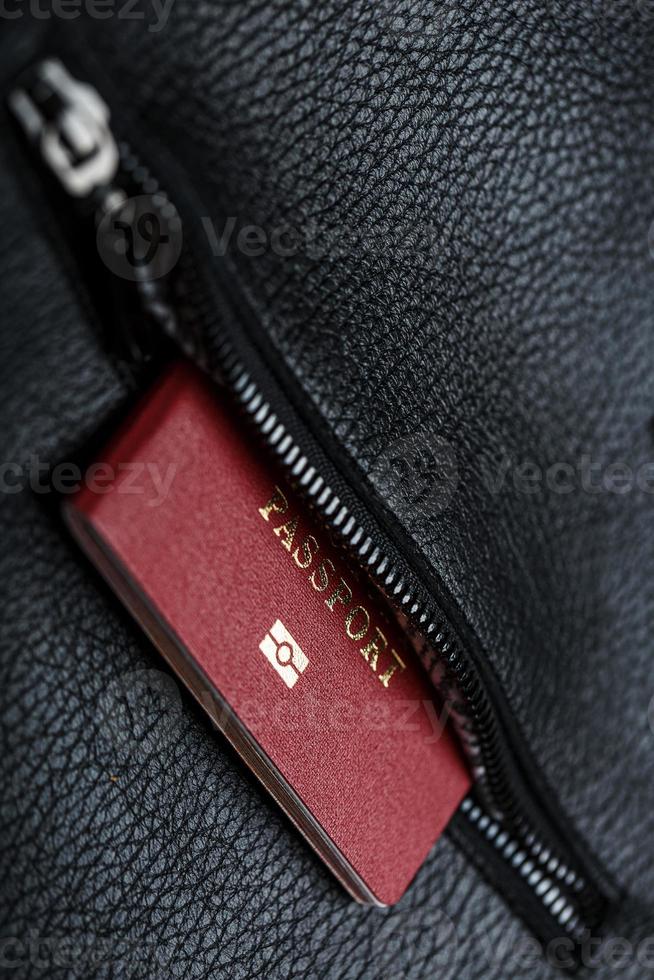 Passport looks out of the pocket of a black leather bag close-up, macro Handmade, natural materials. photo