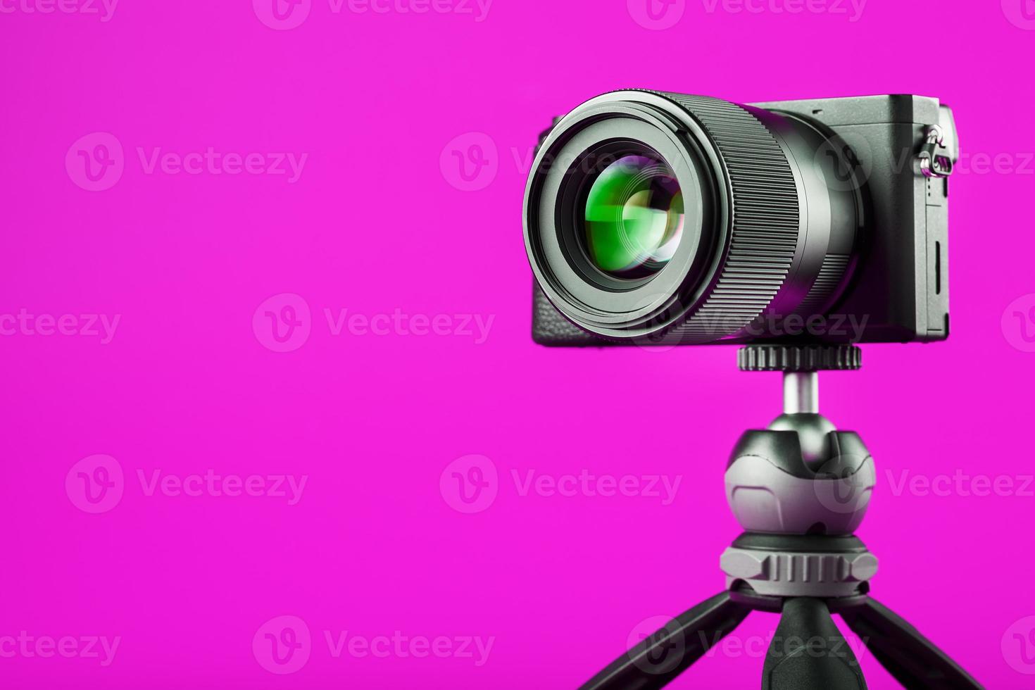 Professional camera on a tripod, on a pink background. Record videos and photos for your blog or report.