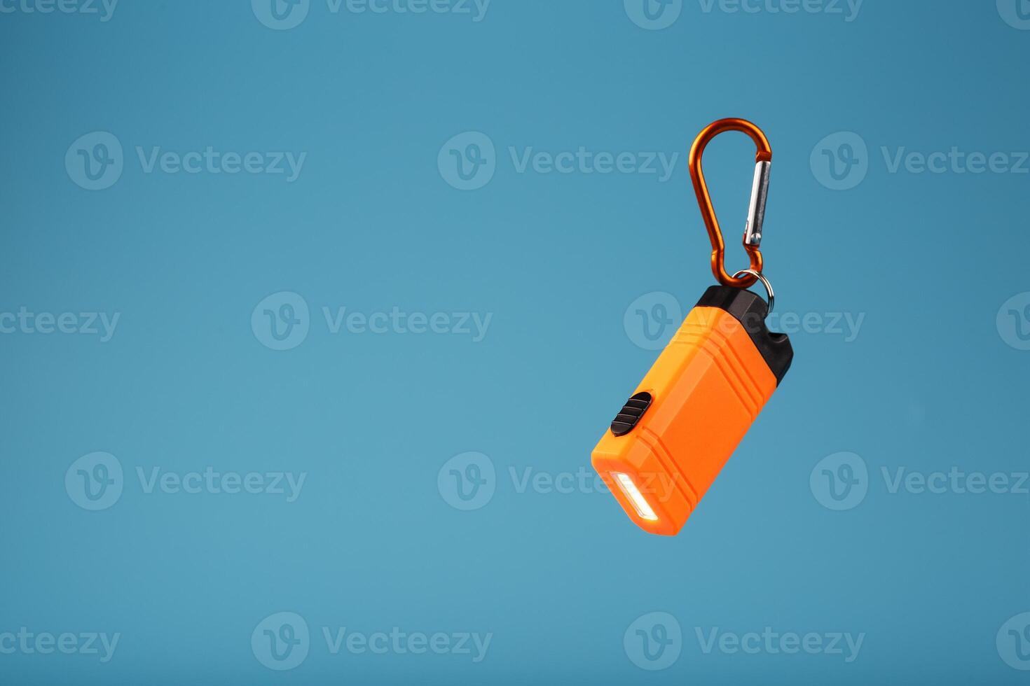 Orange led Flashlight with a carabiner on a blue background. LED lights