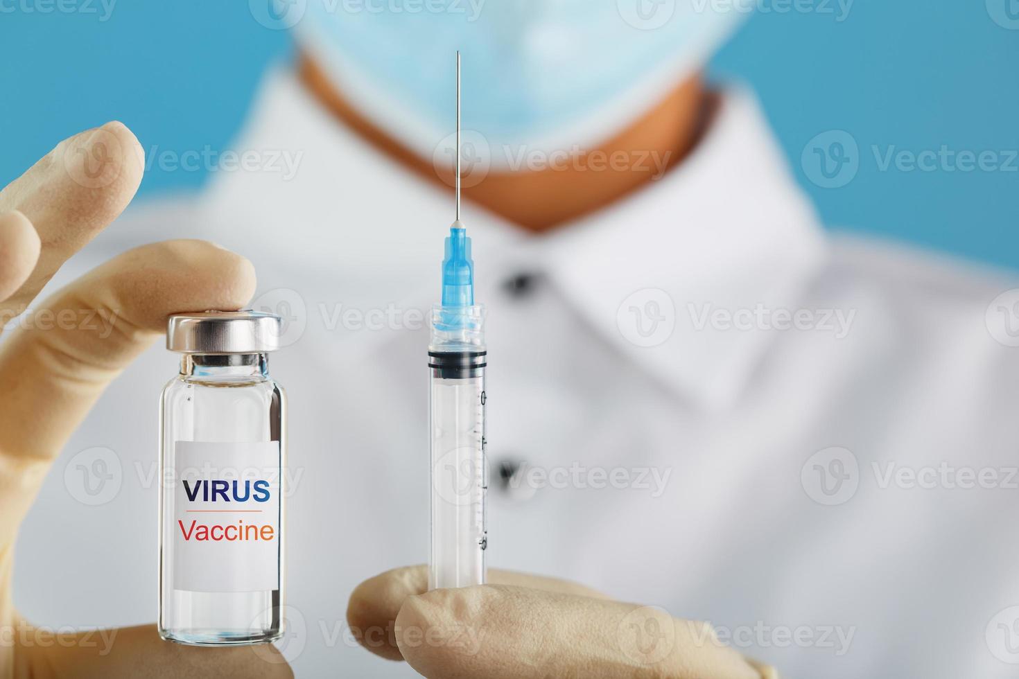 una ampolla con la vacuna del virus de la inscripción y una jeringa en manos de un médico científico con guantes de goma con un primer plano de la vacuna. foto