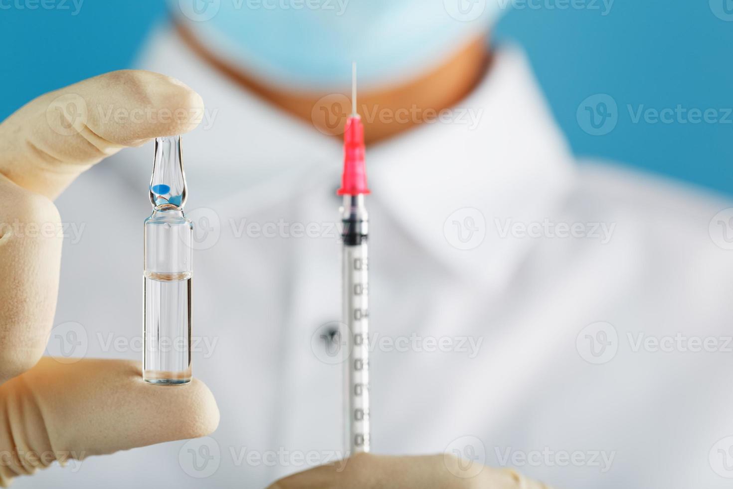 ampolla con la vacuna contra el virus de enfermedades de fondo azul en manos de un médico, científico con guantes y máscara. foto