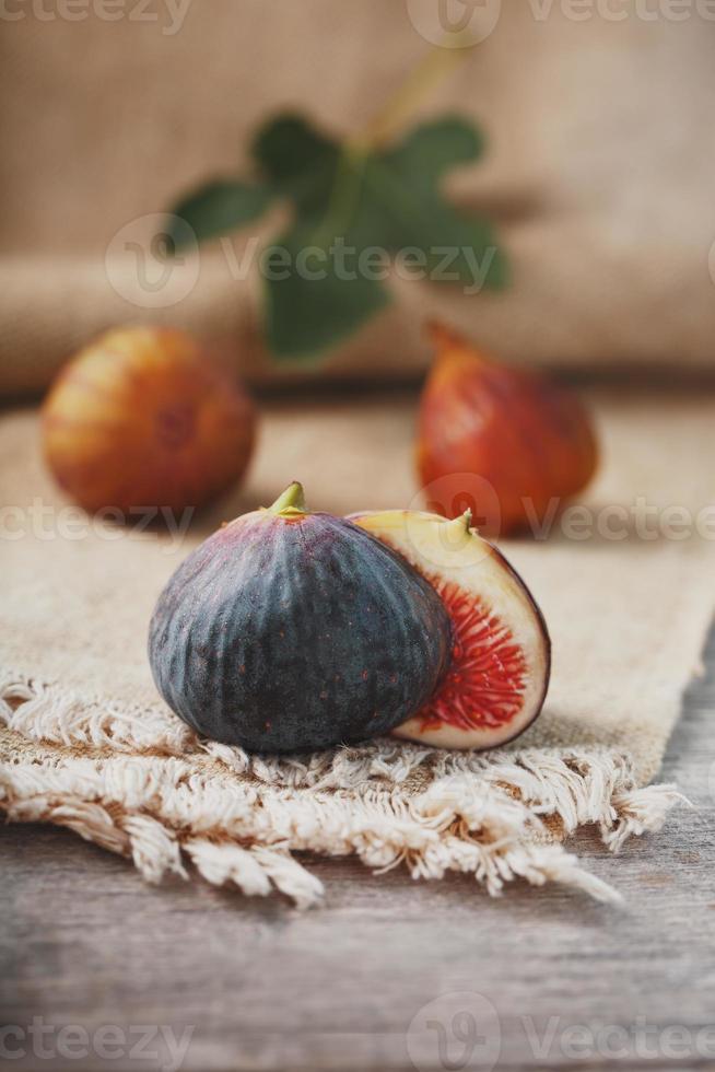 Figs on the table, group of fruits on a wooden farm table with burlap cloth. Slices of fig with pulp. Healthy and tasty fruit photo