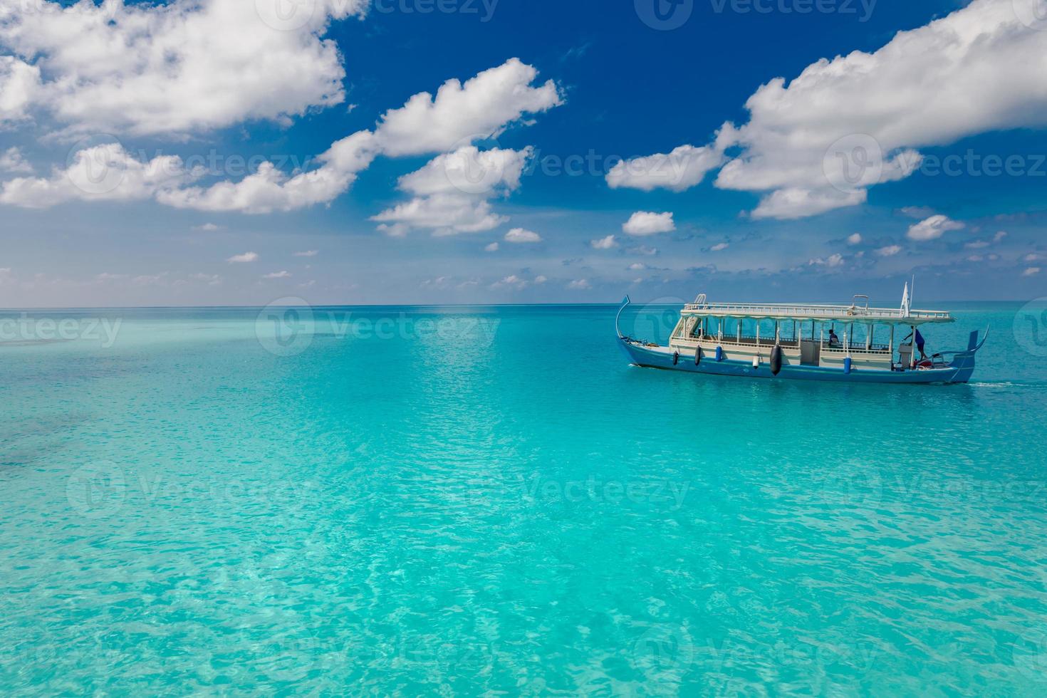 Wonderful Maldivian boat Dhoni on tropical blue sea, taking tourist to snorkeling and diving to see underwater wildlife. Landscape of beach and coast with view of seascape photo