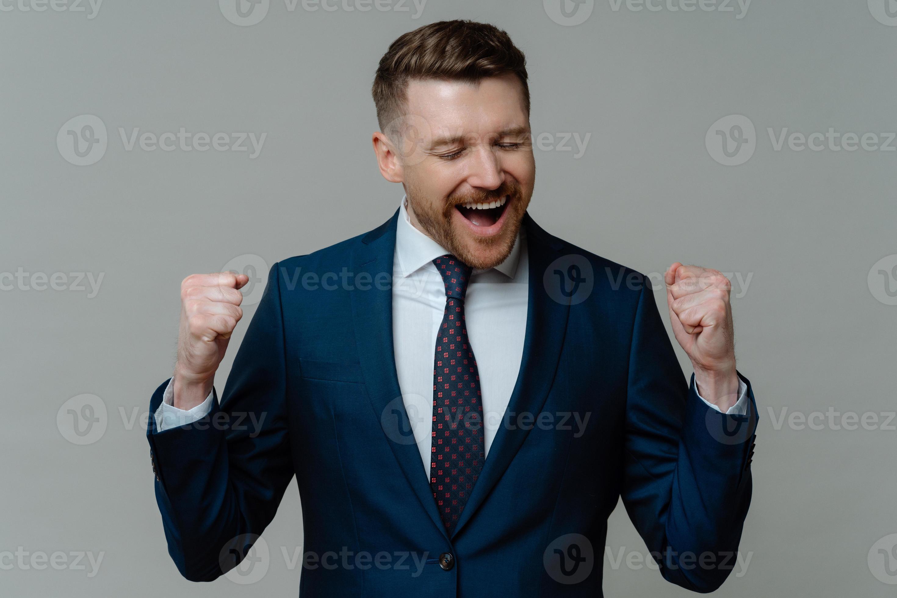 Cheerful excited bearded businessman makes yes gesture clenches fists Cheerful excited bearded businessman makes yes gesture clenches fists