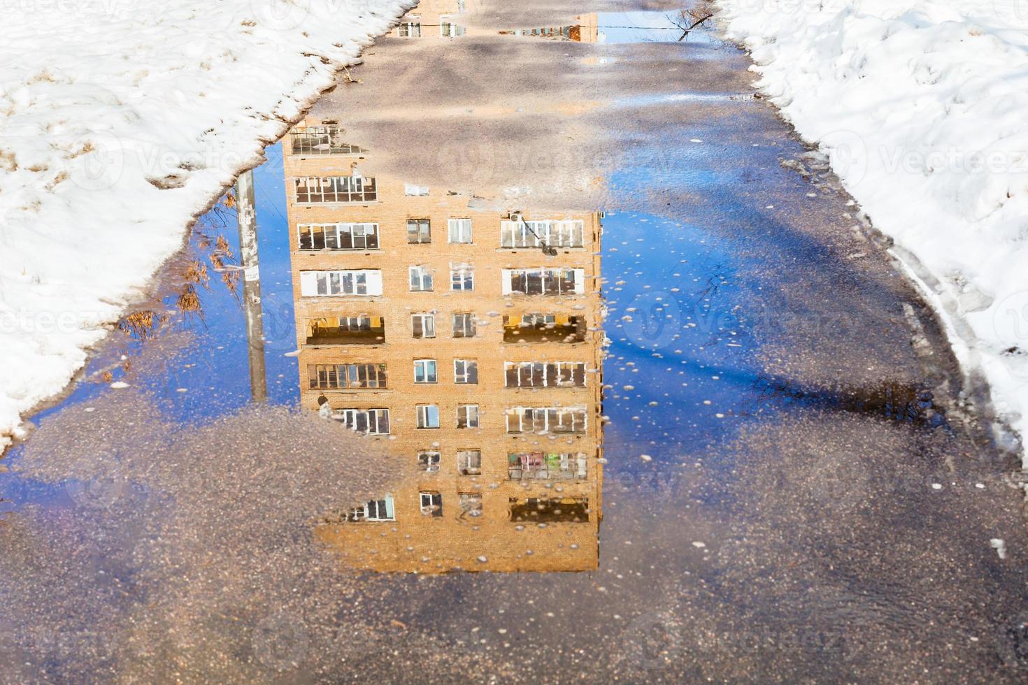 reflection of house in puddle of melting snow photo