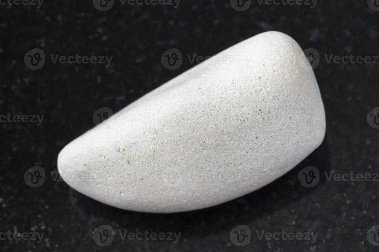 polished white Limestone gemstone on dark photo