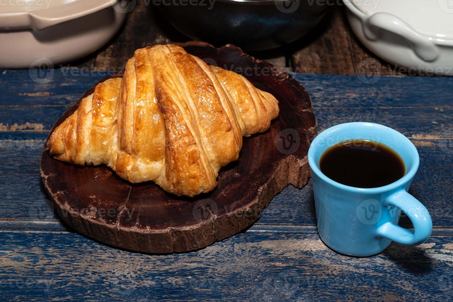 Breakfast food croissant in plate and coffee on wood table. photo