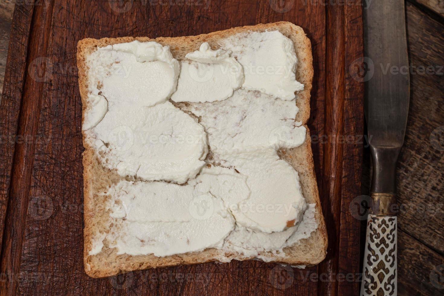 Bread has cream cheese on wood background. photo