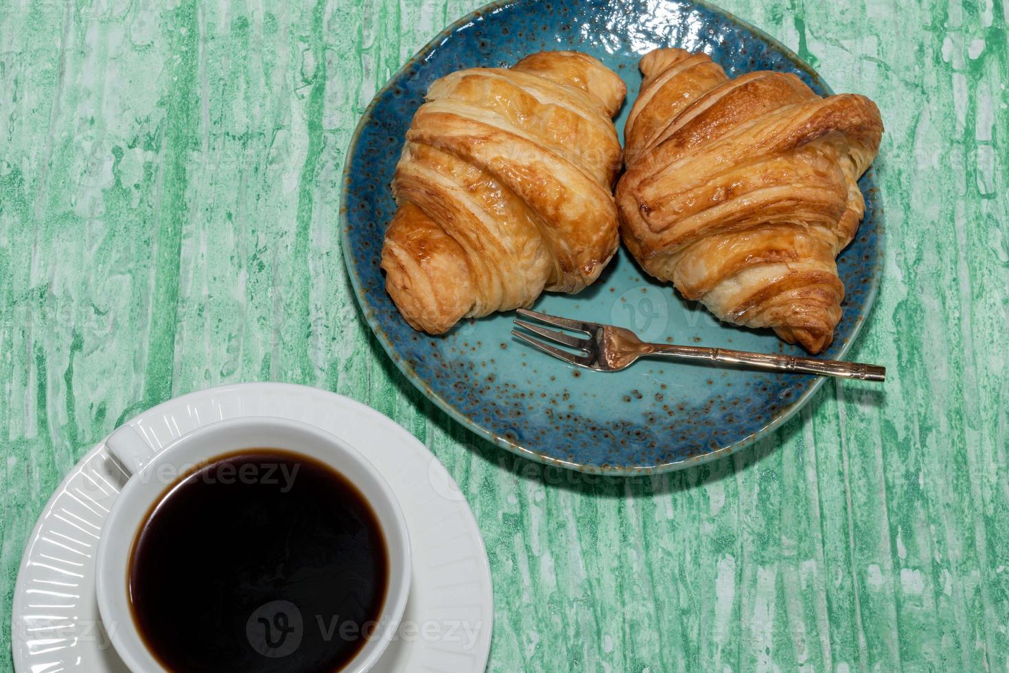 desayuno comida café y croissant en mesa verde aislada. foto