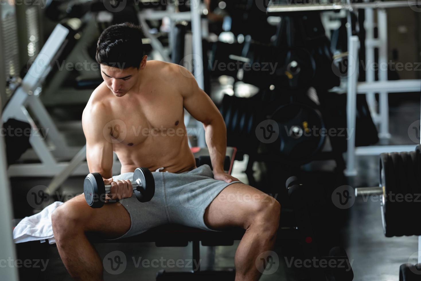 entrenamiento de hombre joven, levantando pesas para desarrollar músculo en fitness en el gimnasio. foto