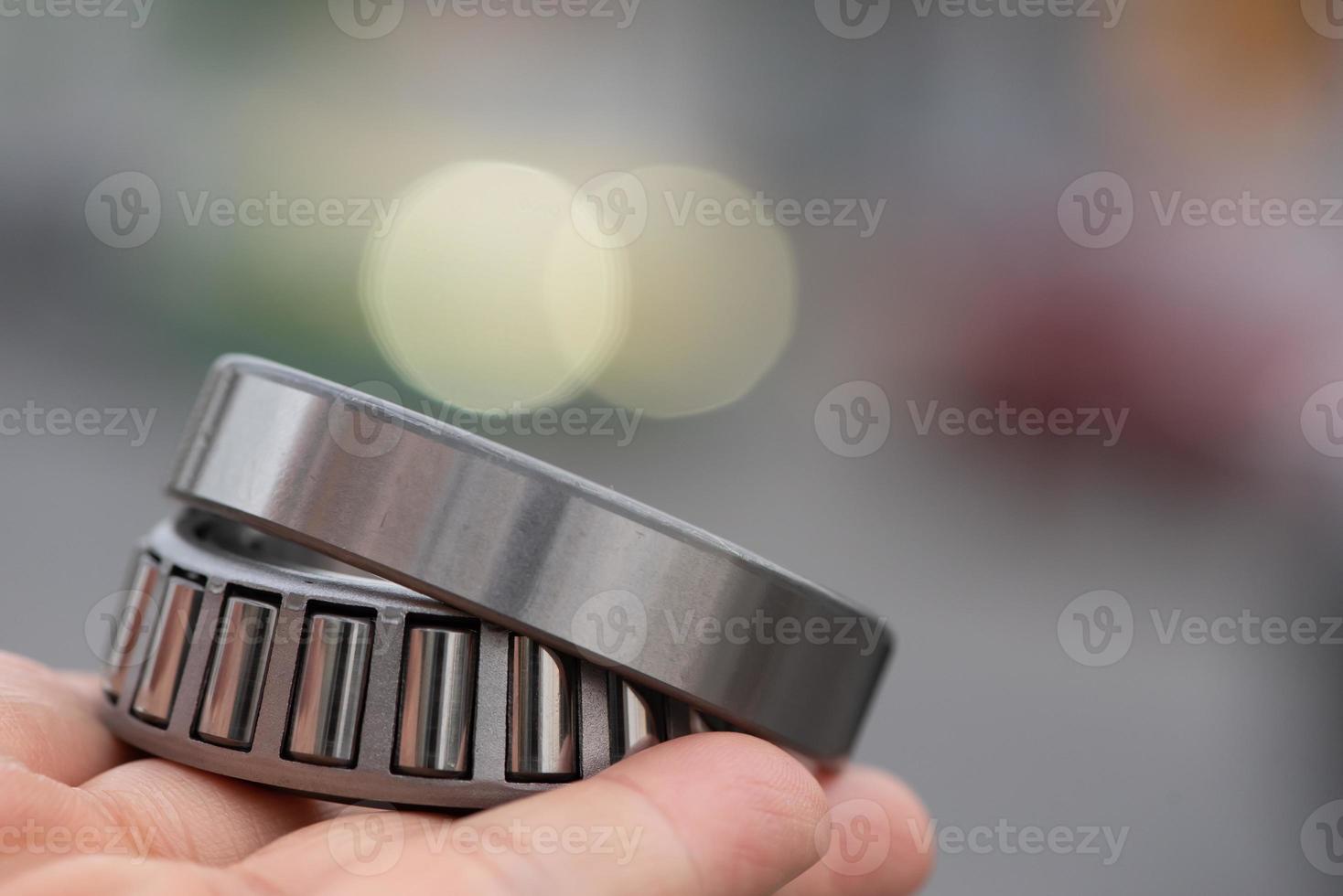 Hand holding Automotive wheel tapered roller bearing on road background, Car Maintenance Service with copy space. photo