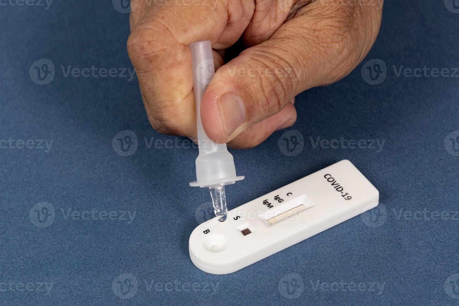 Covid-19 rapid test with person dripping the reagent photo