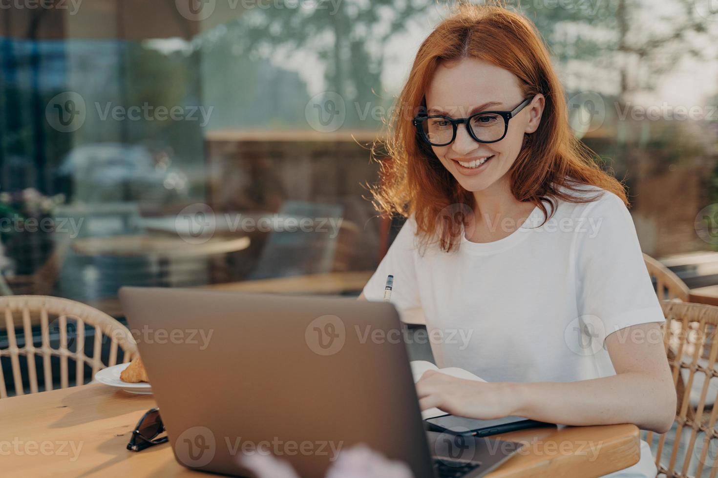 una estudiante ocupada positiva se prepara para los exámenes busca información en Internet a través de una computadora portátil foto
