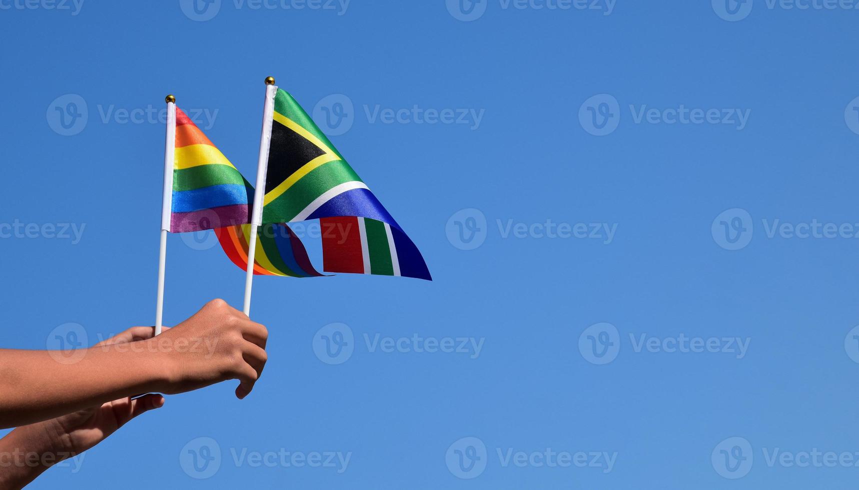 South Africa and rainbow flag, LGBT symbol, holding in hands, bluesky background, concept for LGBT celebration in south africa in pride month, June, soft and selective focus, copy space. photo