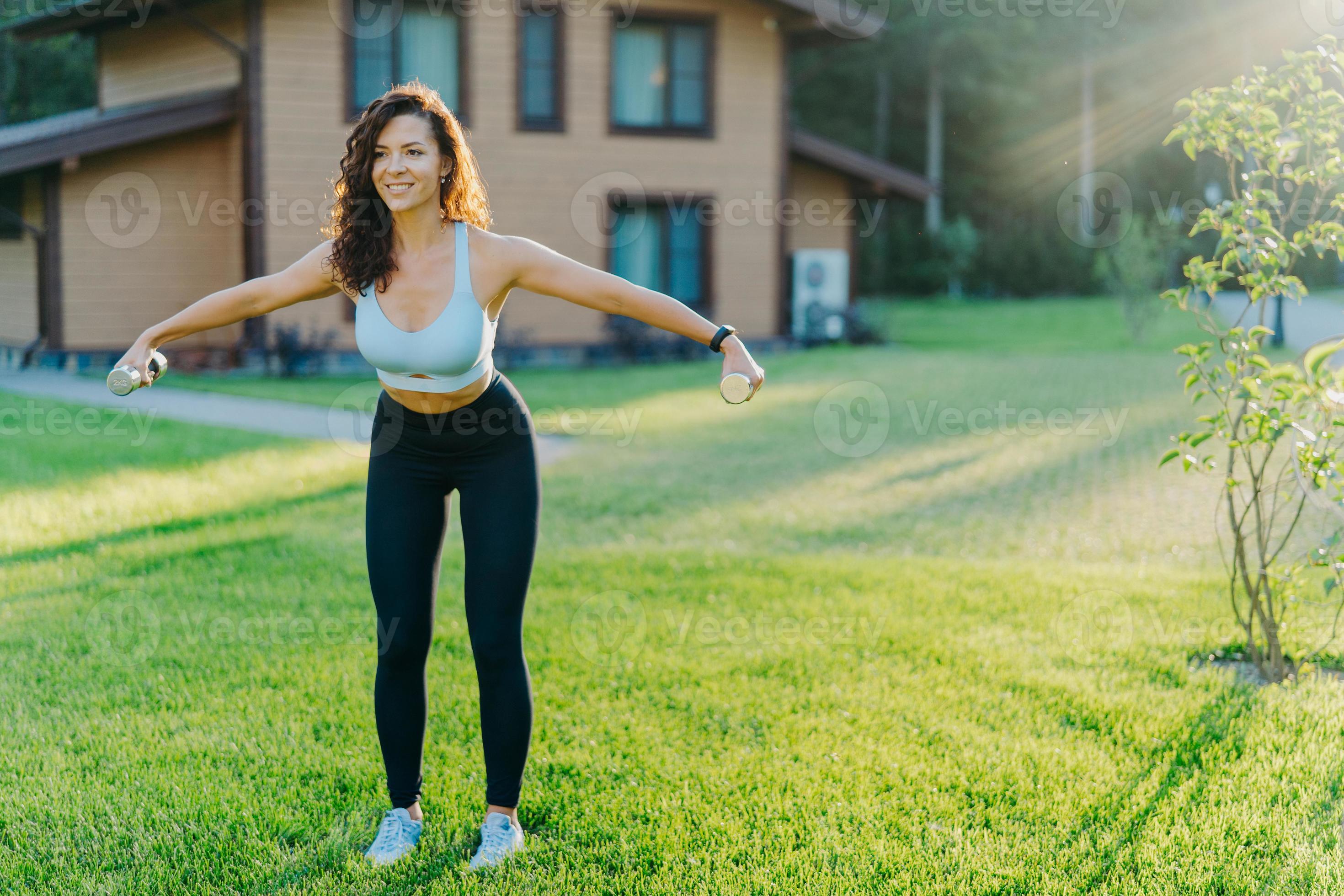 Slim motivated brunette woman dressed in cropped top and leggings