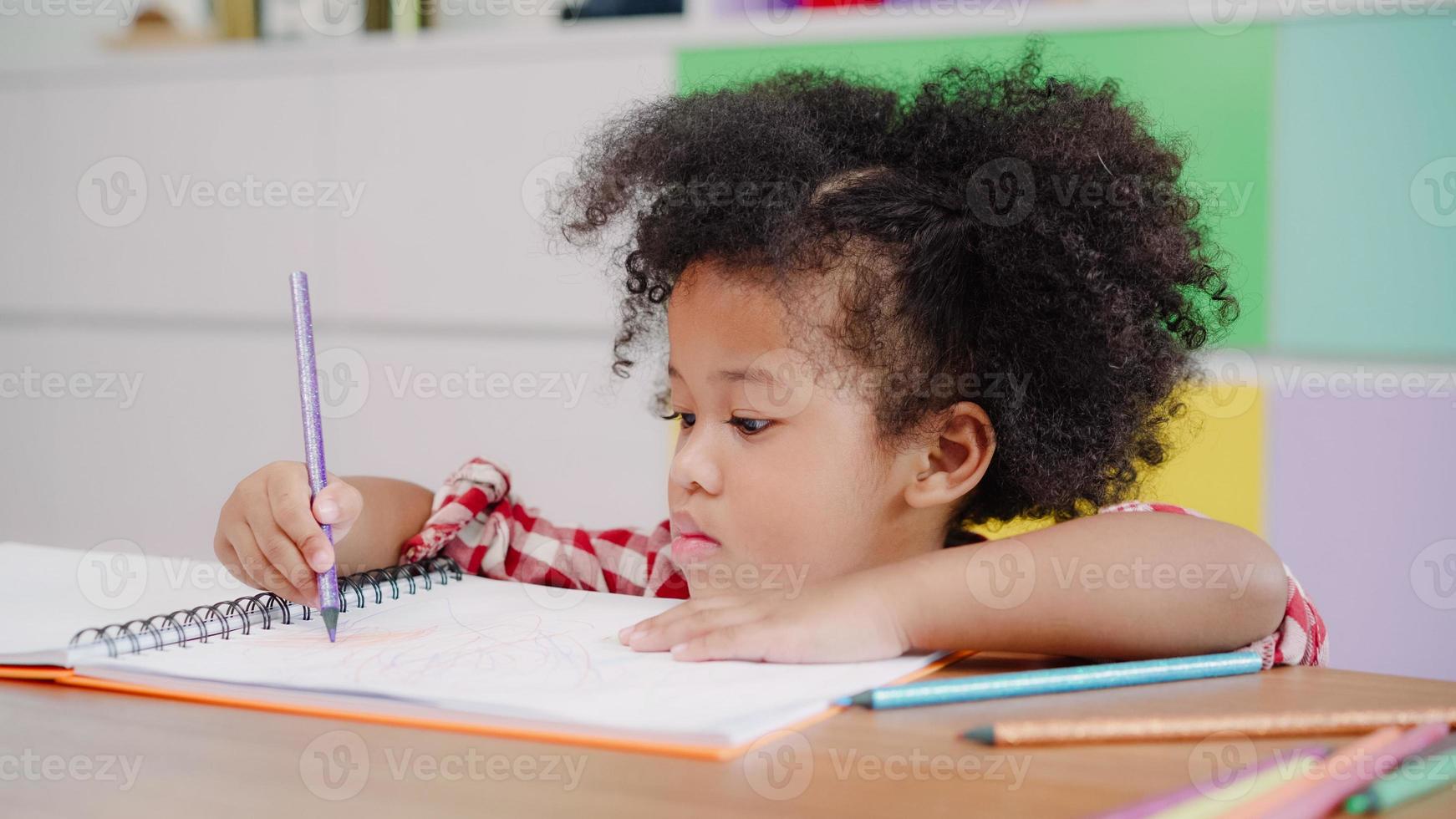 African kids drawing and do homework in classroom, young girl happy funny study and play painting on paper at elementary school. Kid drawing and painting at school concept. photo