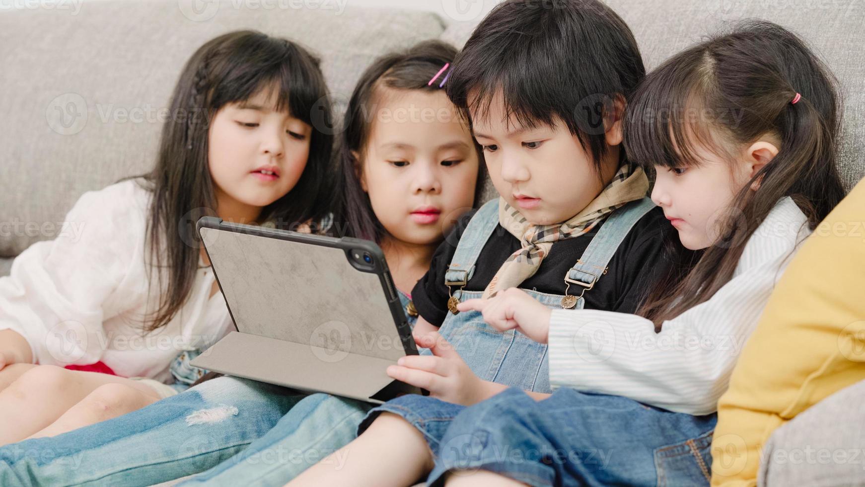 grupo de niños que usan tabletas en el aula, niños y niñas multiétnicos felices usando tecnología para estudiar y jugar en la escuela primaria. los niños usan la tecnología para el concepto de educación. foto