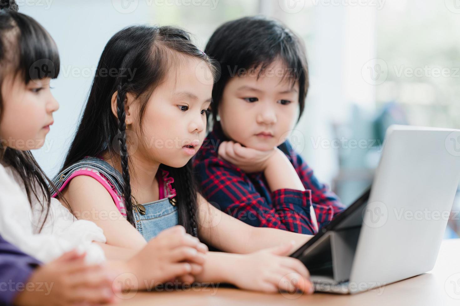 grupo de niños que usan laptop en el aula, niños y niñas multiétnicos felices usando tecnología para estudiar en la escuela primaria. los niños usan la tecnología para el concepto de educación. foto