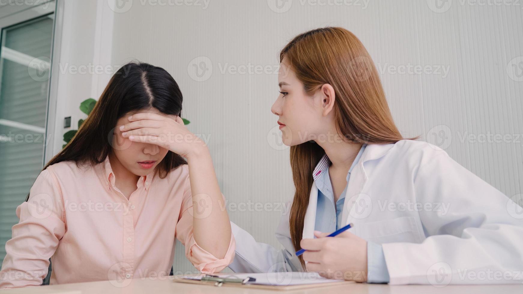 médico hablando con un paciente adolescente infeliz en la sala de examen. una doctora asiática anima y apoya a un paciente con cáncer después de consultar y examinar la salud en una clínica médica u hospital. foto