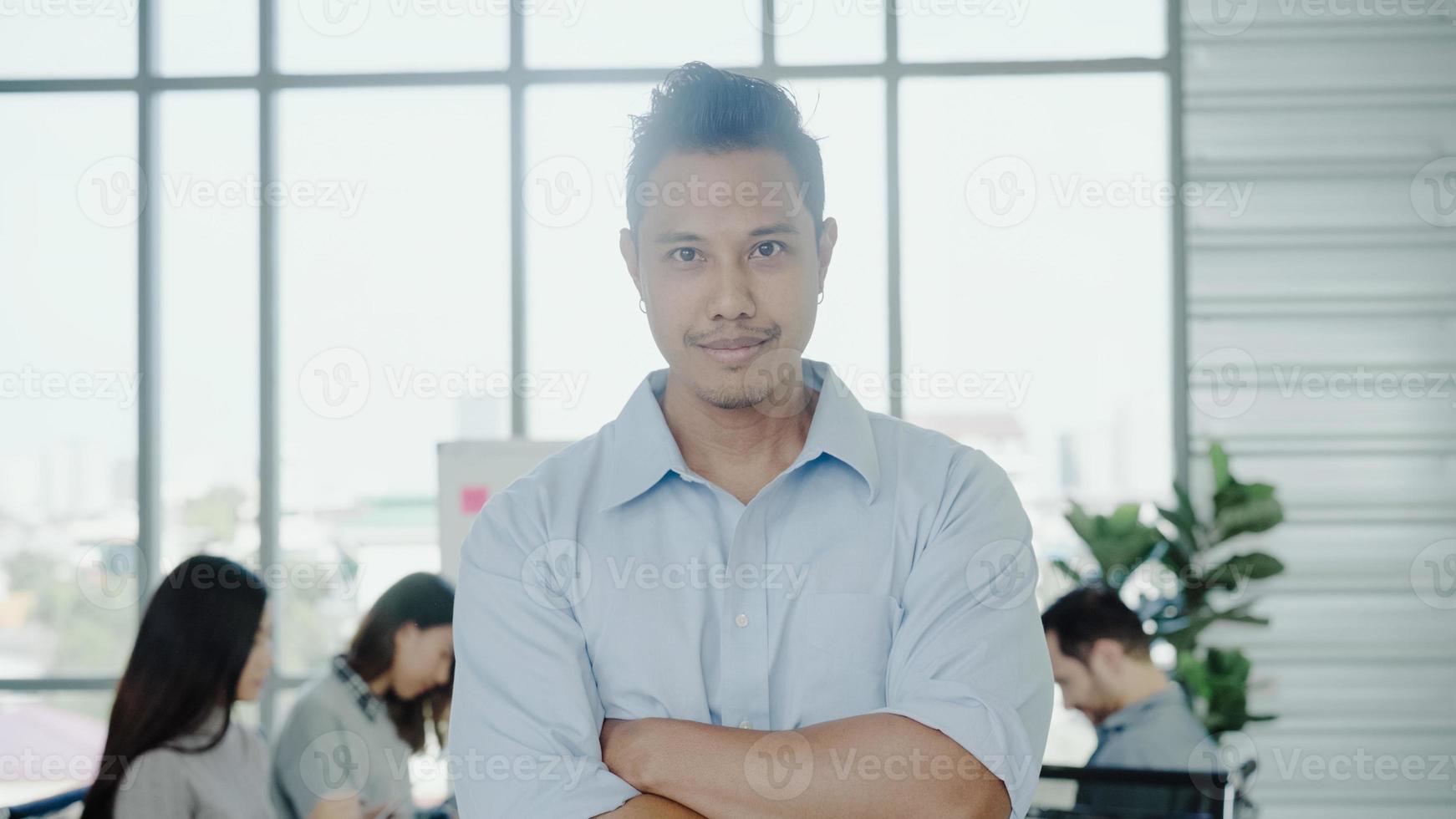 retrato de un exitoso y apuesto hombre de negocios creativo asiático sonriendo a la cámara mientras trabaja en la oficina. hombre de negocios de estilo de vida en su concepto de lugar de trabajo. foto