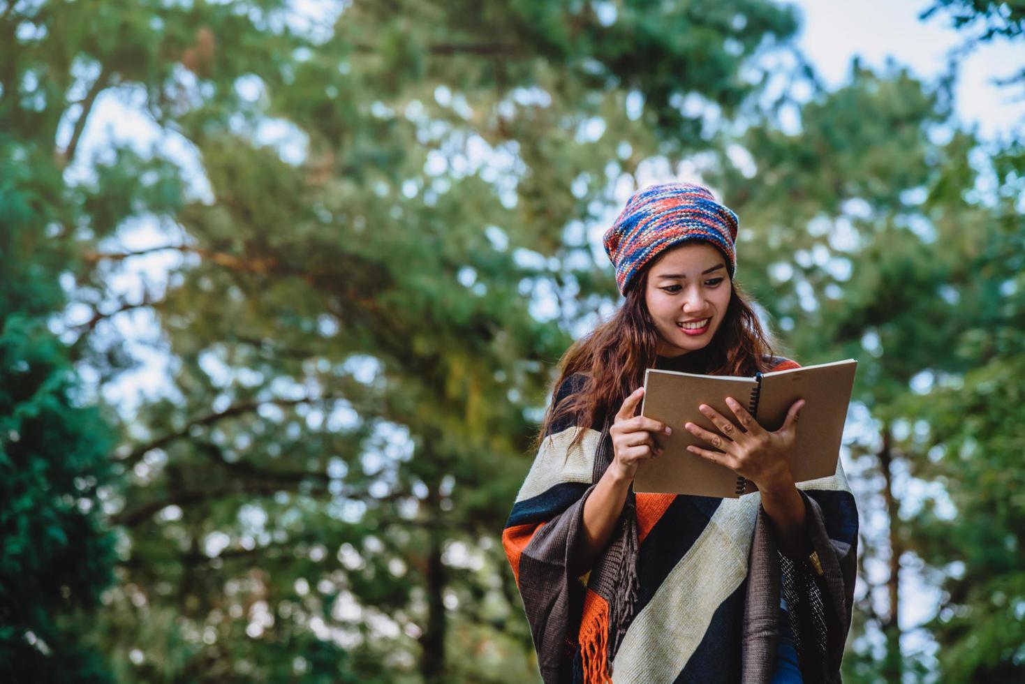 naturaleza de viaje de mujer asiática. viajar relajarse. estudiar leer un libro. educación sobre la naturaleza escribe una nota en un parque público en verano. En Tailandia foto