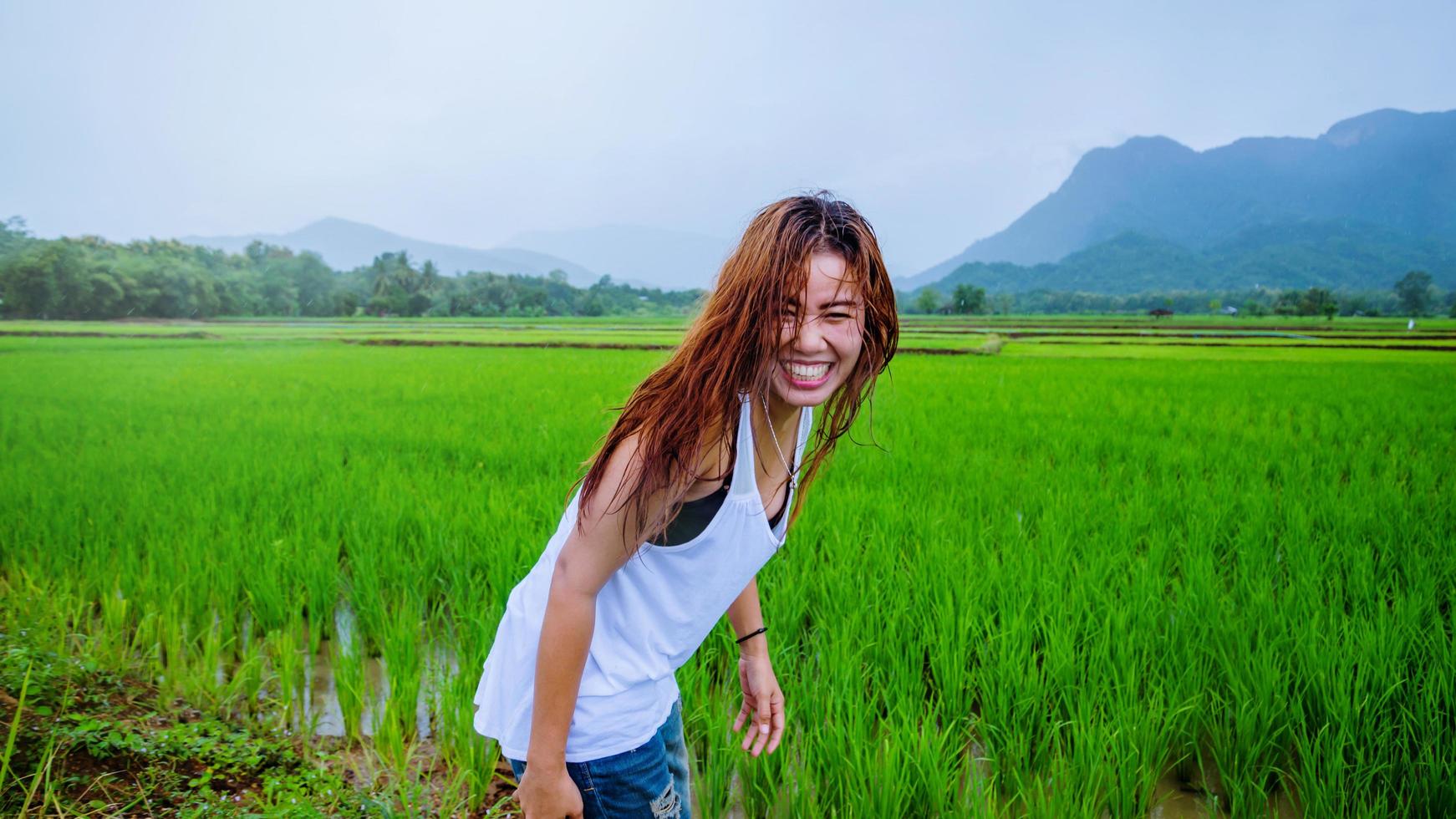 las mujeres asiáticas viajan relajarse en las vacaciones. la niña sonrió feliz y disfrutó de la lluvia que caía. viajando en campiña, campos de arroz verde, viaje a tailandia. foto