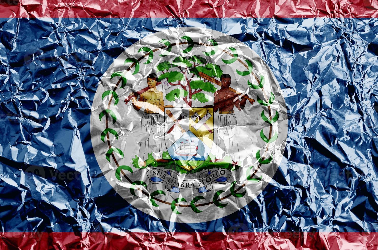 Belize flag depicted in paint colors on shiny crumpled aluminium foil closeup. Textured banner on rough background photo