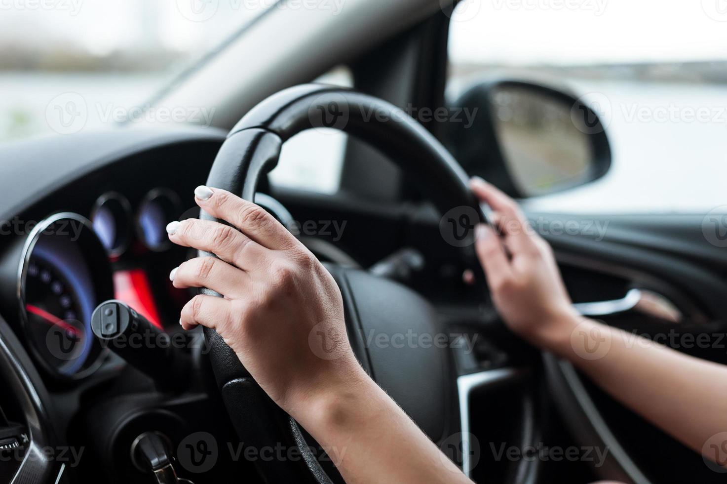 Women's hands on the steering wheel, inside the car. photo