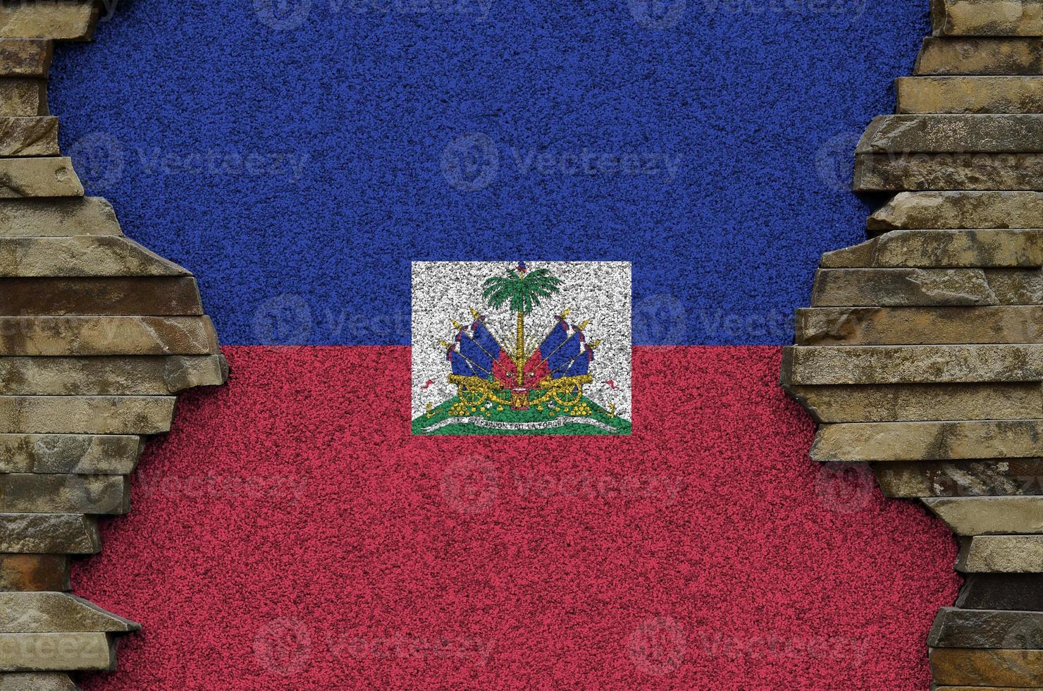 bandera de haití representada en colores de pintura en el primer plano de la pared de piedra antigua. banner texturizado sobre fondo de pared de roca foto