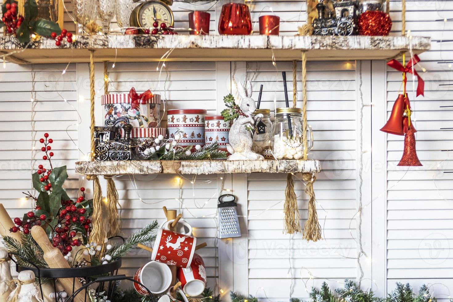 Table in the kitchen with kitchen utensils and shelves decorated with Christmas toys photo