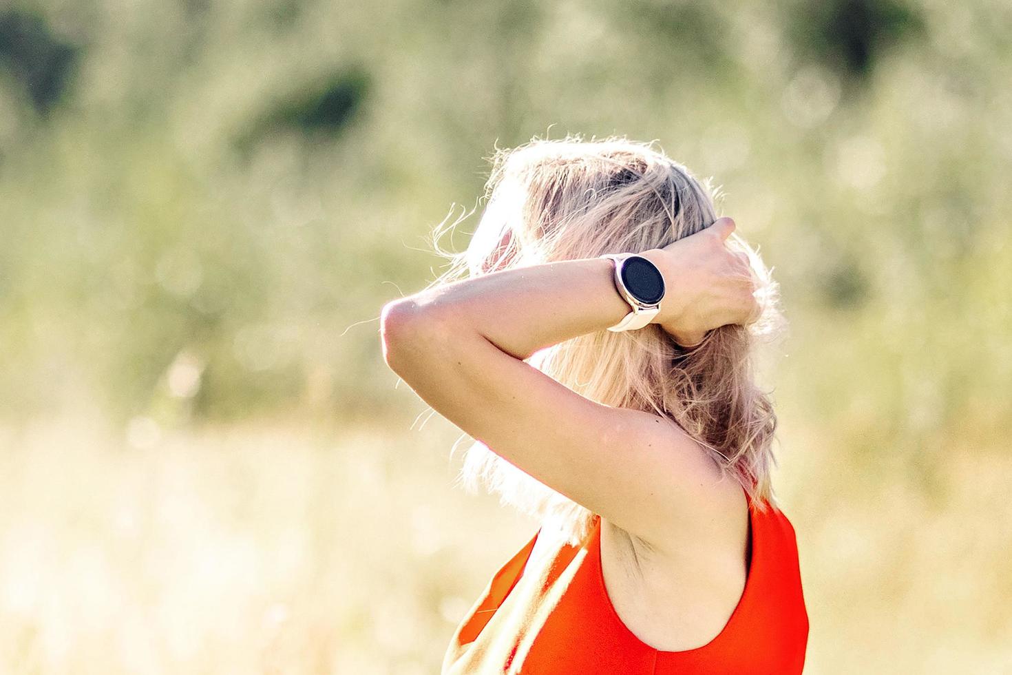 A young blonde woman in a bright dress stands in the middle of the field with her arms outstretched. Happiness, freedom, summer, vacation photo