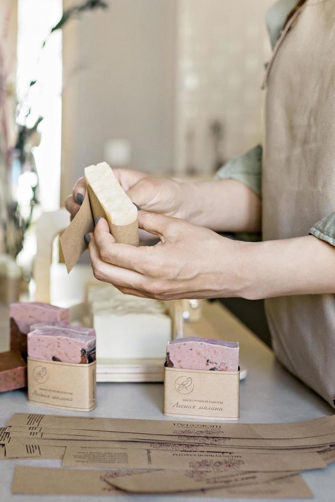 una niña fabricante de jabón sostiene un trozo de jabón hecho a mano recién hecho en sus manos.el proceso de preparación y empaque.spa en el hogar.pequeña empresa foto